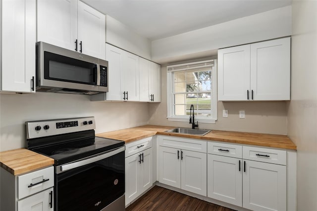 kitchen with stainless steel appliances, a sink, wooden counters, and white cabinets