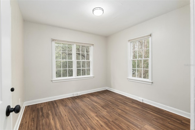 spare room with baseboards and wood finished floors