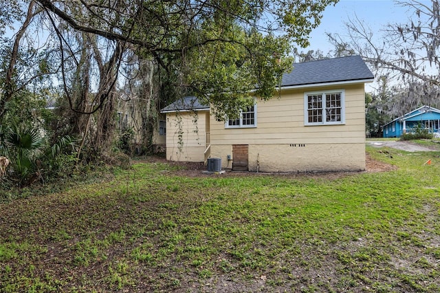 rear view of house featuring a shingled roof, crawl space, a lawn, and central air condition unit