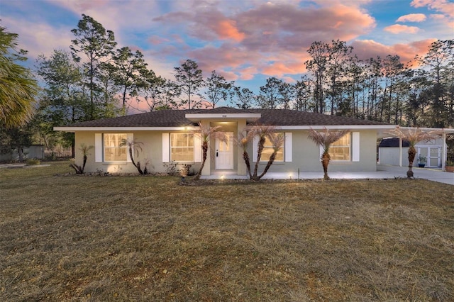 single story home featuring concrete driveway, an attached carport, a lawn, and stucco siding