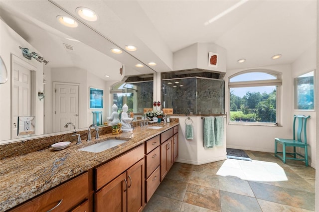 full bathroom featuring a sink, visible vents, vaulted ceiling, a shower stall, and double vanity