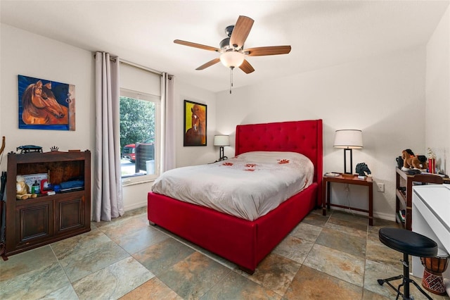 bedroom featuring stone finish floor, ceiling fan, and baseboards