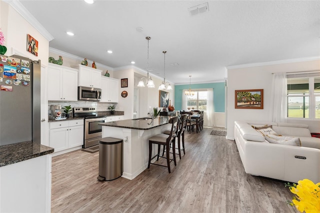 kitchen with light wood finished floors, stainless steel appliances, visible vents, open floor plan, and white cabinetry