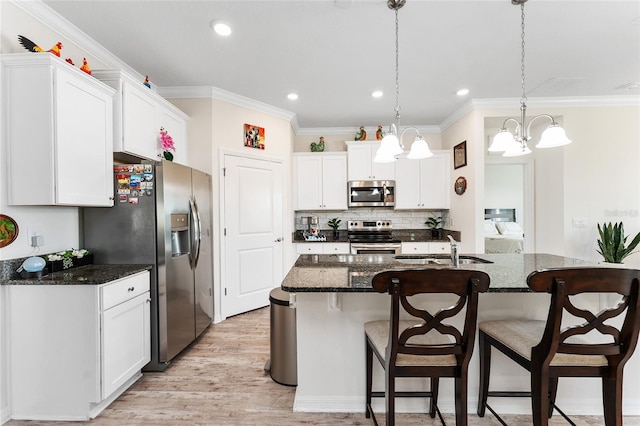 kitchen featuring appliances with stainless steel finishes, a kitchen bar, a sink, and light wood-style flooring