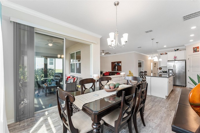 dining area with light wood-style floors, visible vents, crown molding, and ceiling fan with notable chandelier