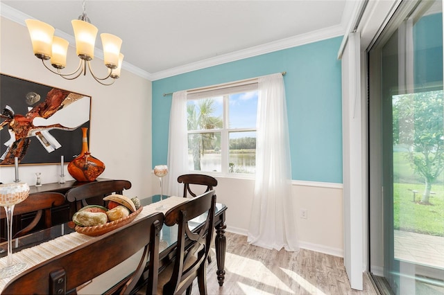 dining area with light wood finished floors, ornamental molding, a chandelier, and baseboards