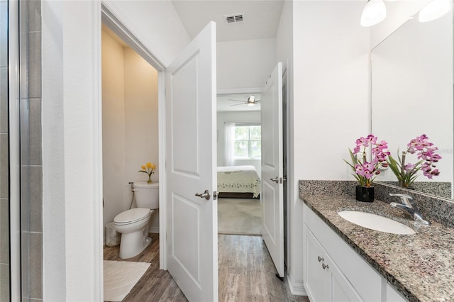 ensuite bathroom featuring visible vents, toilet, vanity, ensuite bath, and wood finished floors