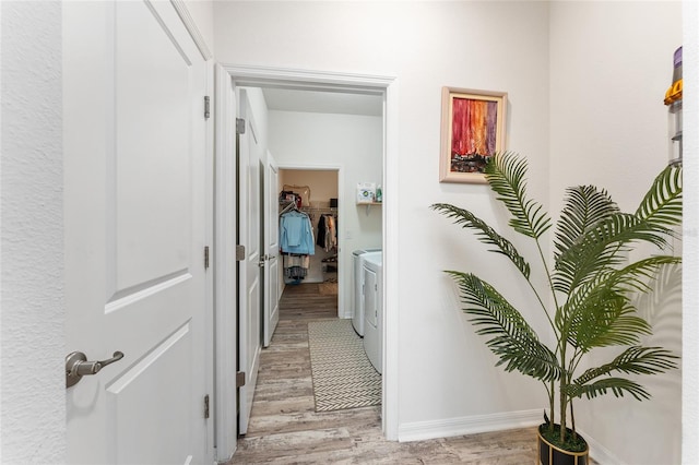 hall featuring light wood-style flooring, baseboards, and washer and clothes dryer