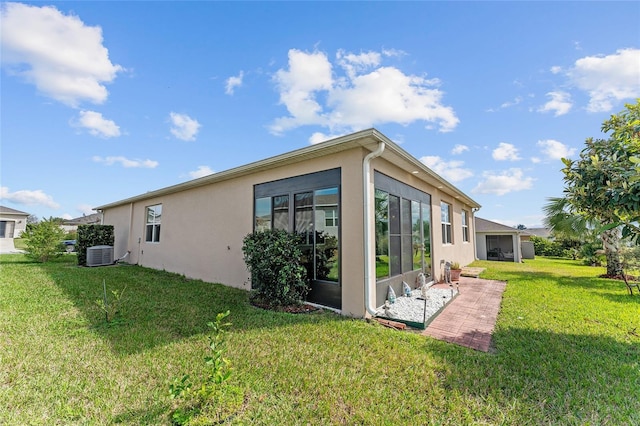 view of property exterior featuring central air condition unit, a lawn, a sunroom, and stucco siding