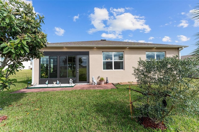 back of property with a yard and stucco siding