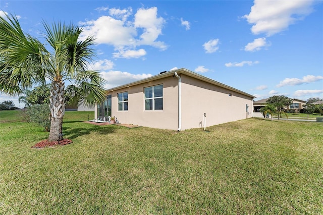 rear view of property with a lawn and stucco siding