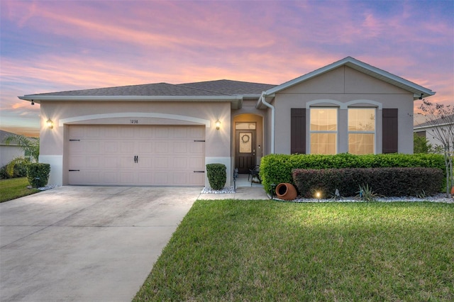 ranch-style home with driveway, a yard, an attached garage, and stucco siding