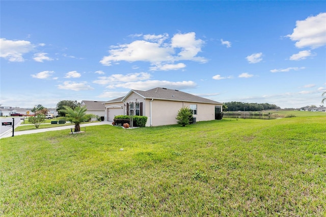 view of side of property with a yard, concrete driveway, an attached garage, and stucco siding