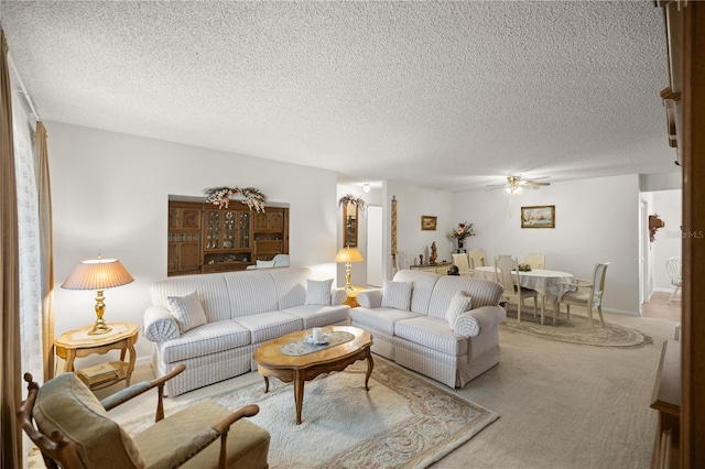 living room featuring light colored carpet, a ceiling fan, and a textured ceiling