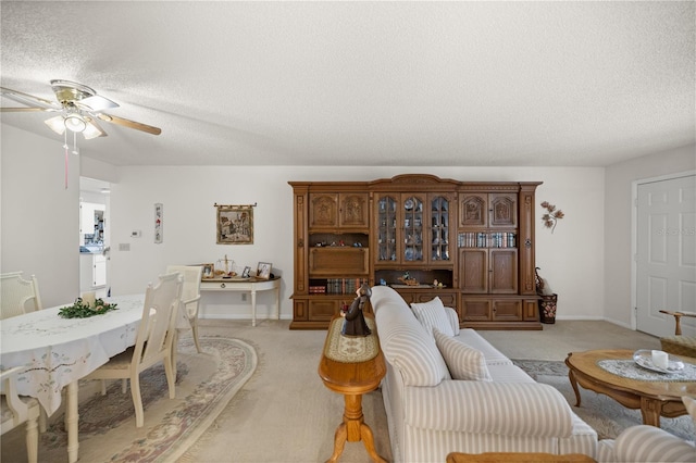 living area with baseboards, light colored carpet, a textured ceiling, and ceiling fan