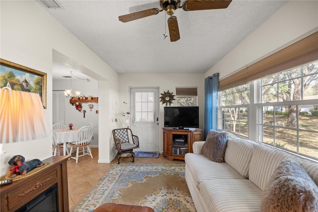 living room with light tile patterned floors, plenty of natural light, a textured ceiling, and ceiling fan with notable chandelier