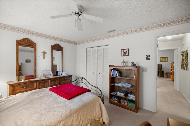 bedroom with visible vents, ceiling fan, a closet, a textured ceiling, and light colored carpet