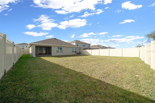 back of house with a fenced backyard, a lawn, and stucco siding