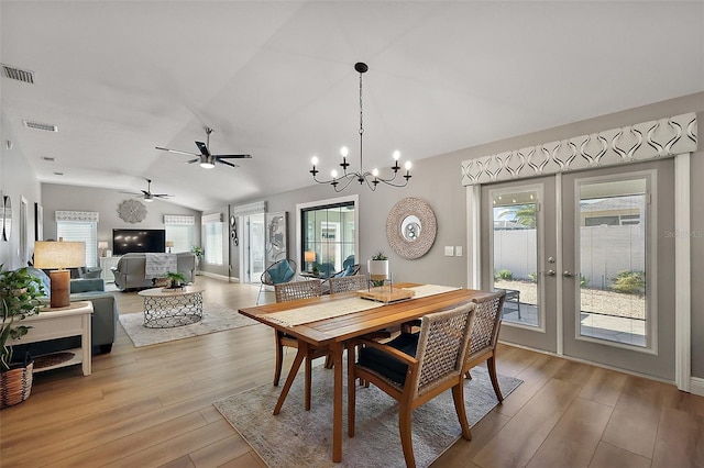 dining room with light wood-type flooring, visible vents, vaulted ceiling, and french doors