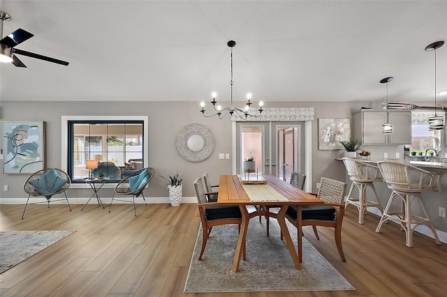 dining area featuring french doors, light wood-style flooring, baseboards, and ceiling fan with notable chandelier