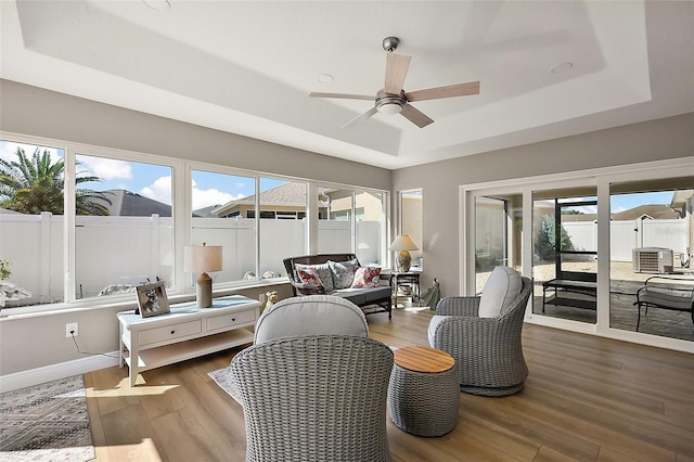 sunroom featuring a ceiling fan, a raised ceiling, and a wealth of natural light