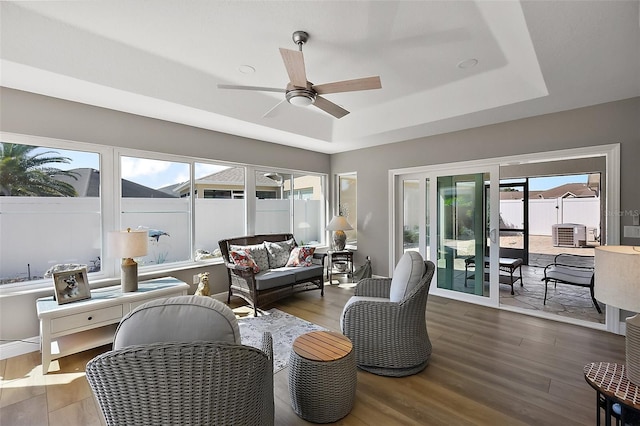 sunroom / solarium featuring a healthy amount of sunlight, ceiling fan, and a tray ceiling