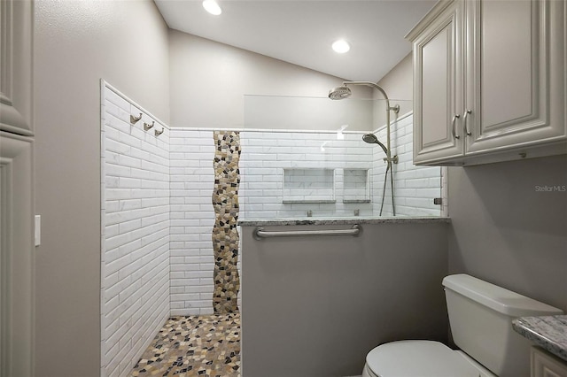 bathroom featuring recessed lighting, tiled shower, vaulted ceiling, and toilet