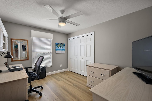 office with light wood-style floors, ceiling fan, a textured ceiling, and baseboards