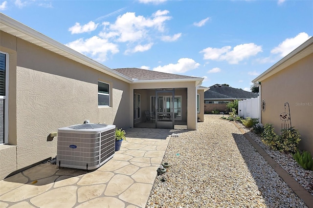 rear view of house featuring a patio, a sunroom, fence, central AC, and stucco siding