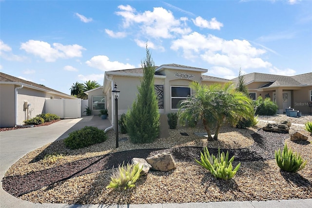 view of front of property featuring driveway, fence, and stucco siding