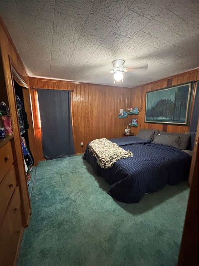 bedroom featuring wooden walls, ceiling fan, and carpet