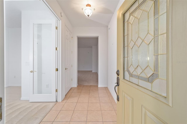 interior space with light carpet, baseboards, and light tile patterned flooring