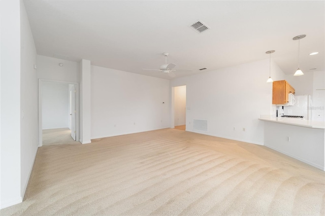 unfurnished living room with visible vents, a ceiling fan, and light colored carpet