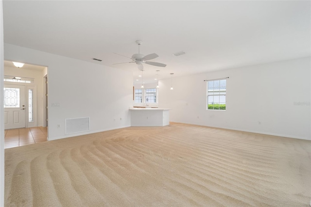 unfurnished living room with light carpet, light tile patterned floors, and visible vents