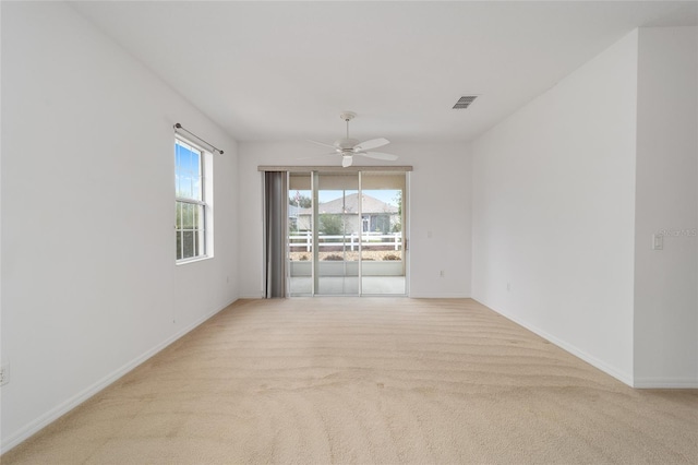 empty room with baseboards, a ceiling fan, visible vents, and light colored carpet