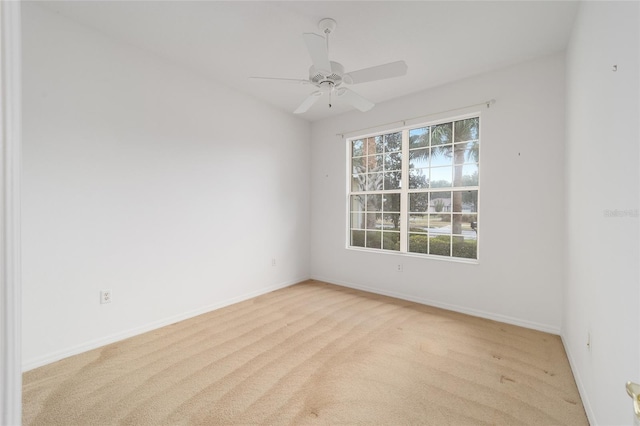 unfurnished room with baseboards, ceiling fan, and light colored carpet