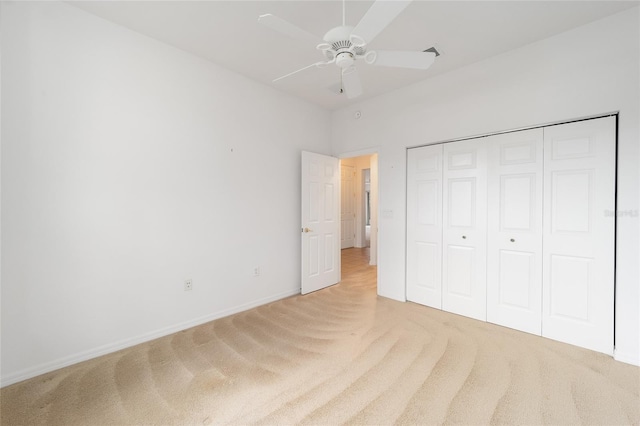 unfurnished bedroom featuring a ceiling fan, a closet, light carpet, and baseboards