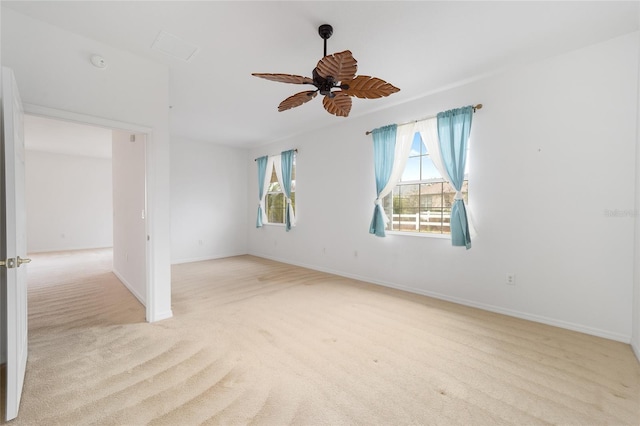 spare room with a ceiling fan, light carpet, and baseboards