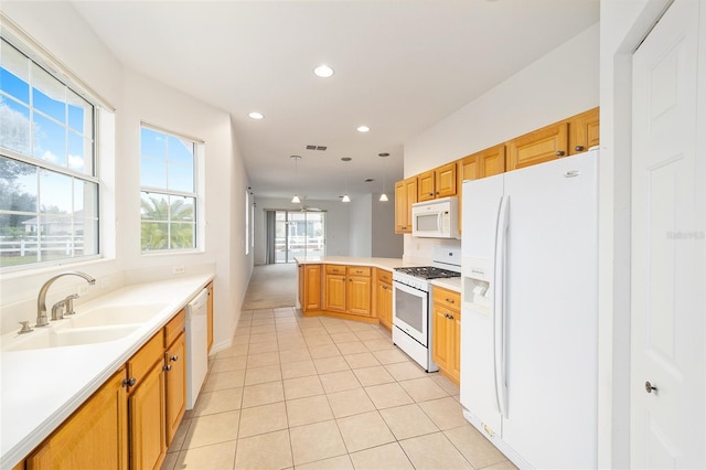 kitchen with white appliances, a peninsula, light countertops, pendant lighting, and a sink