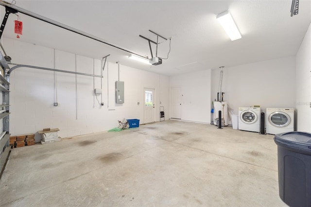 garage with concrete block wall, electric panel, and washing machine and clothes dryer