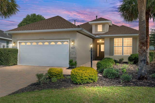 8669 SW 88th Loop, Ocala, FL 34481 - traditional-style house with stucco siding, a garage, driveway, and roof with shingles