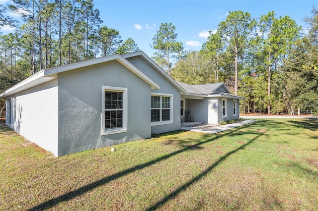 rear view of property with a lawn and stucco siding