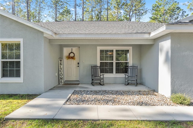 doorway to property featuring a shingled roof, a porch, and stucco siding