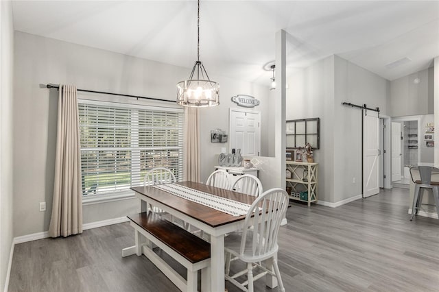 dining area featuring a barn door, wood finished floors, and baseboards