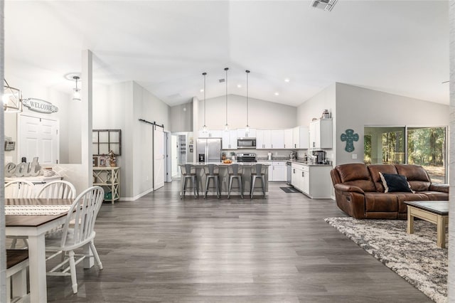 living room featuring a barn door, visible vents, high vaulted ceiling, and dark wood finished floors