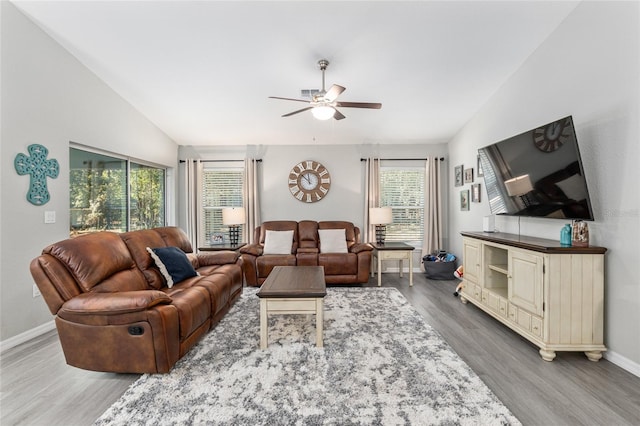 living area with lofted ceiling, ceiling fan, baseboards, and wood finished floors