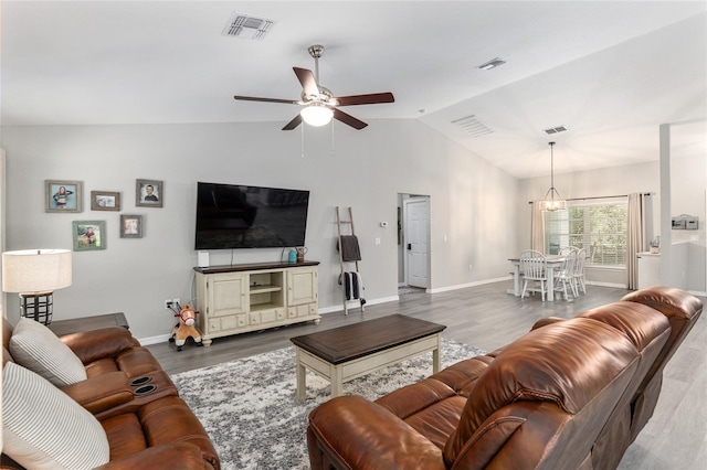 living area with lofted ceiling, visible vents, and wood finished floors