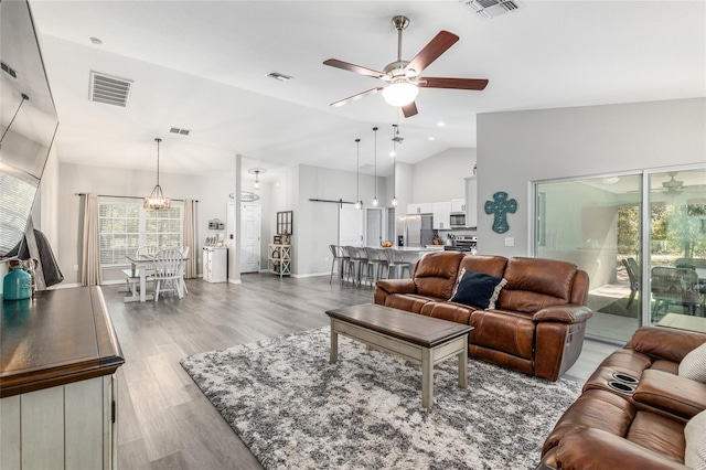 living area with a ceiling fan, visible vents, and wood finished floors