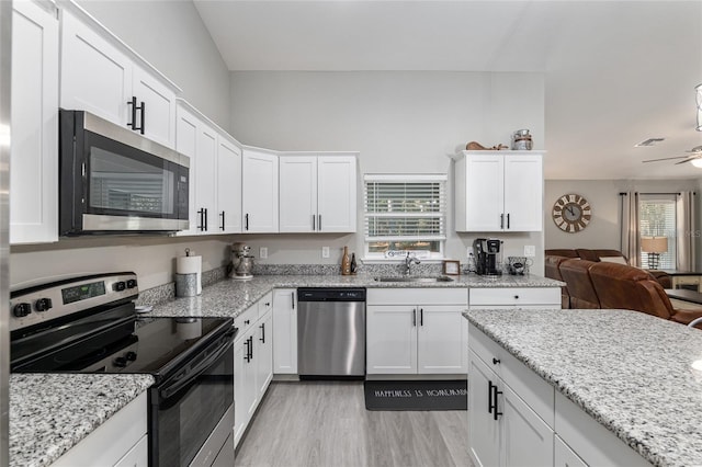 kitchen with open floor plan, stainless steel appliances, a sink, and white cabinets