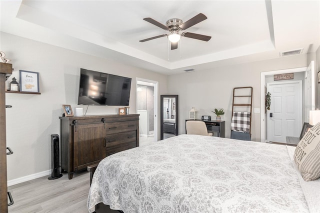 bedroom with visible vents, a tray ceiling, and baseboards